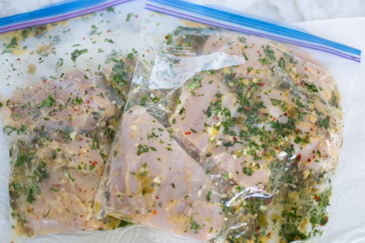raw chicken in zip top bags with cilantro lime green chile marinade