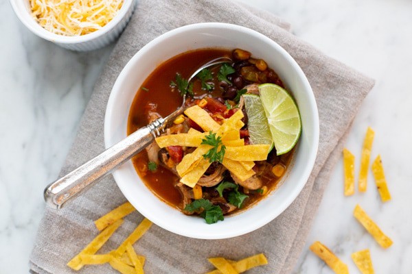 Easy Chicken Tortilla Soup is a hearty, delicious soup filled with chicken, green chile, corn, and black beans in a tomato broth. This soup is full of flavor without being too spicy. Serve it with fried tortilla strips and cheese for the ultimate Tex-Mex lunch or dinner!