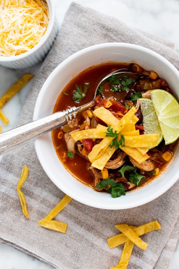 Easy Chicken Tortilla Soup is a hearty, delicious soup filled with chicken, green chile, corn, and black beans in a tomato broth. This soup is full of flavor without being too spicy. Serve it with fried tortilla strips and cheese for the ultimate Tex-Mex lunch or dinner!