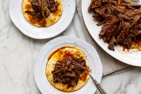 instant pot beef brisket on a white plate with grits