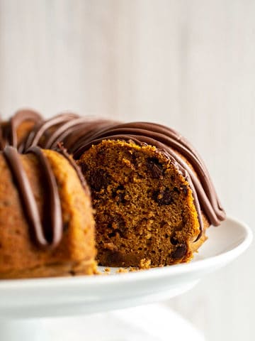 a pumpkin chocolate chip bundt cake on a white cake stand