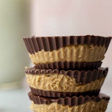 stack of 3 sunbutter cups with a glass of milk in the background