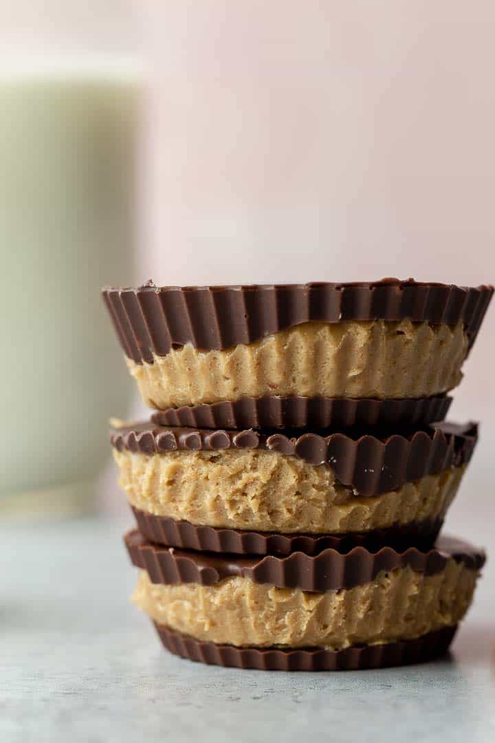 stack of 3 sunbutter cups with a glass of milk in the background