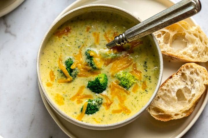 bowl of easy broccoli cheese soup with a spoon and bread