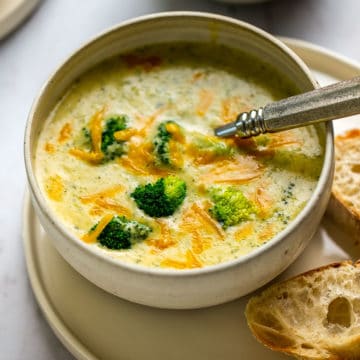bowl of easy broccoli cheese soup with a spoon and sliced bread