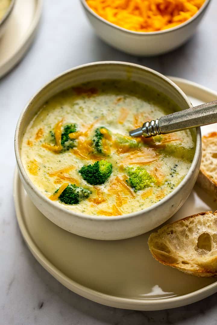 bowl of easy broccoli cheese soup with a spoon and sliced bread 