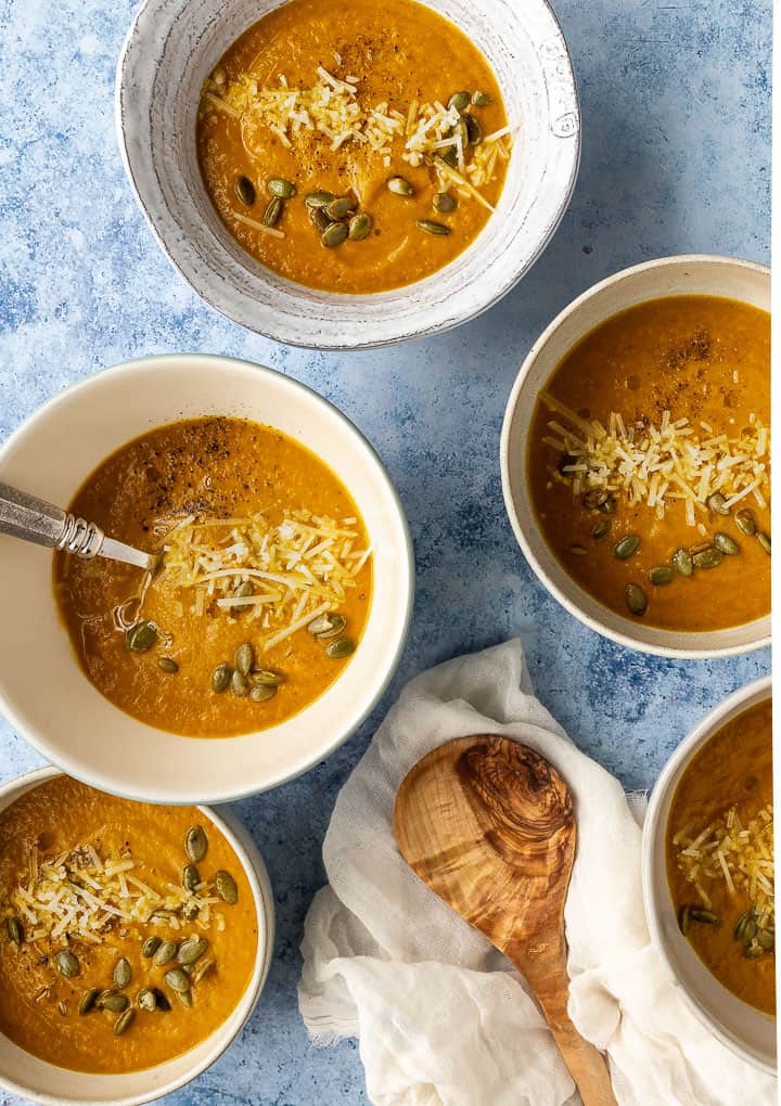 several bowls of pumpkin soup on a blue background