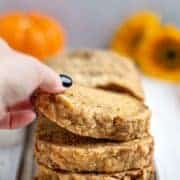 hand picking up a piece of sliced banana pumpkin bread