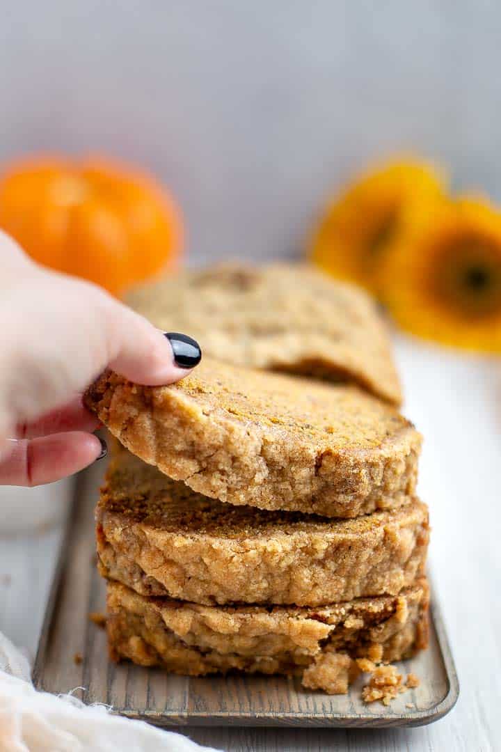 hand picking up a piece of sliced banana pumpkin bread