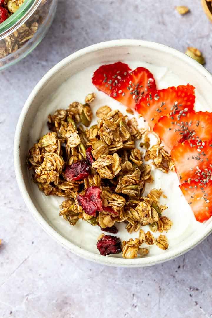 Granola and sliced strawberries over yogurt in a white bowl