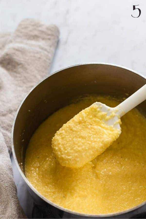 grits mixture in a pan with a white spatula