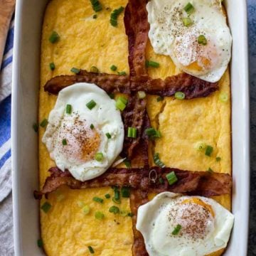 white casserole pan with grits, bacon strips and 3 fried eggs