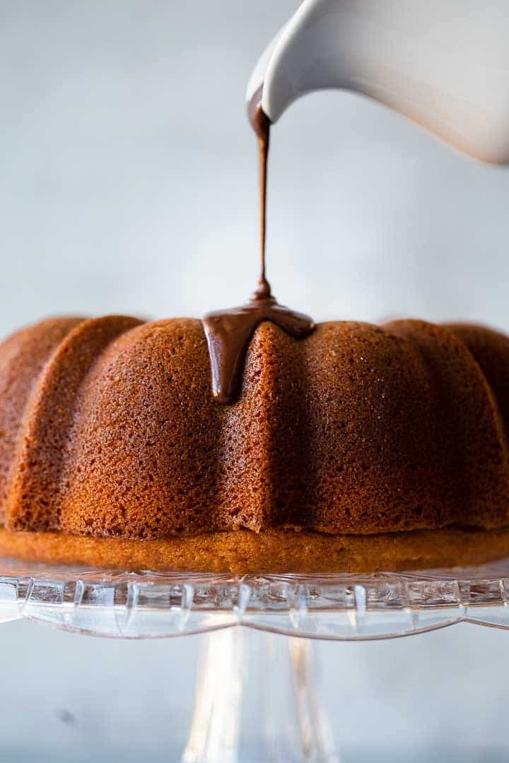 chocolate ganache being poured over a bundt cake