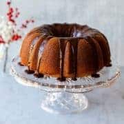 butterscotch bundt cake on a crystal cake stand with red berries in the background