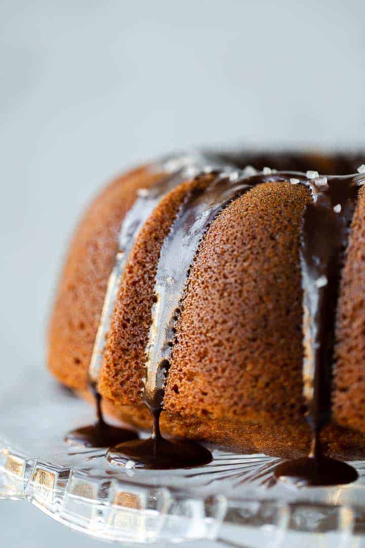 butterscotch bundt cake on a crystal cake stand with chocolate ganche and sea salt