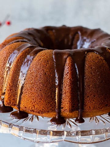 butterscotch bundt cake on a crystal cake stand with red and white flowers in the background