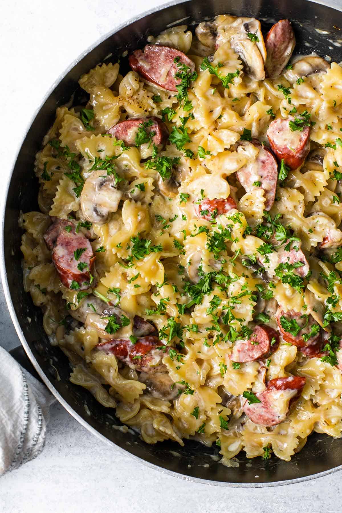 skillet with a creamy pasta dish sprinkled with parsley