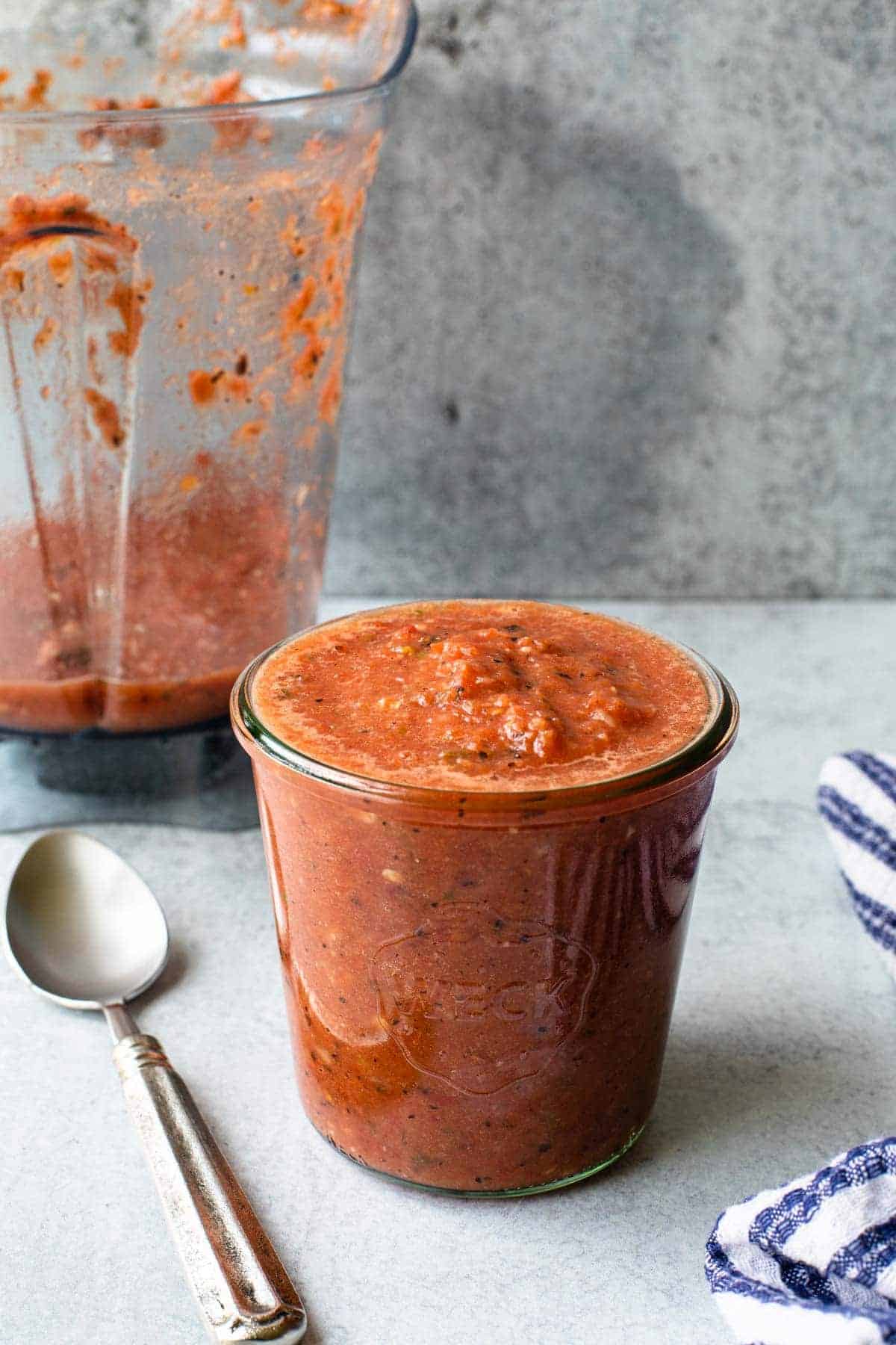 jar of salsa with spoon next to it and blender container in background