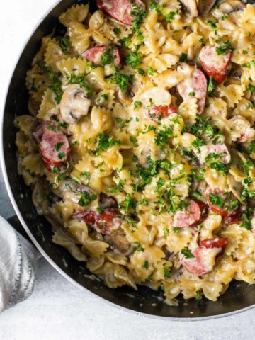 skillet with a creamy pasta dish sprinkled with parsley