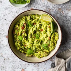 overhead view of a bowl of guacamole with a lime wedge