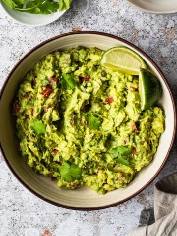 overhead view of a bowl of guacamole with a lime wedge