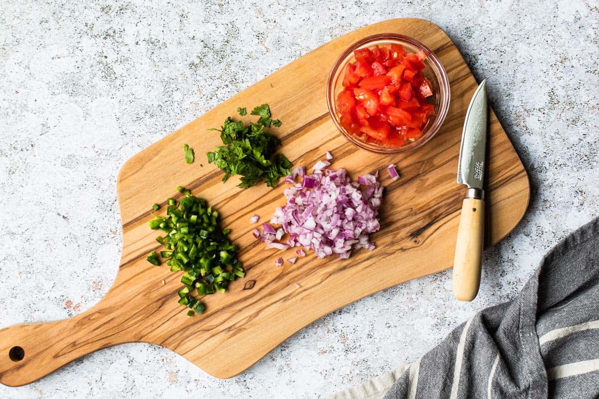 chopped produce on a cutting board with a knife off to side