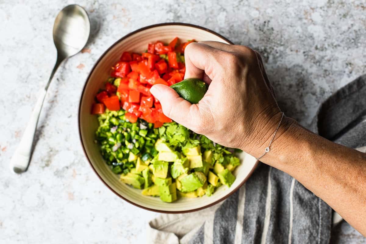 hand squeezing lime into bowl of ingredients