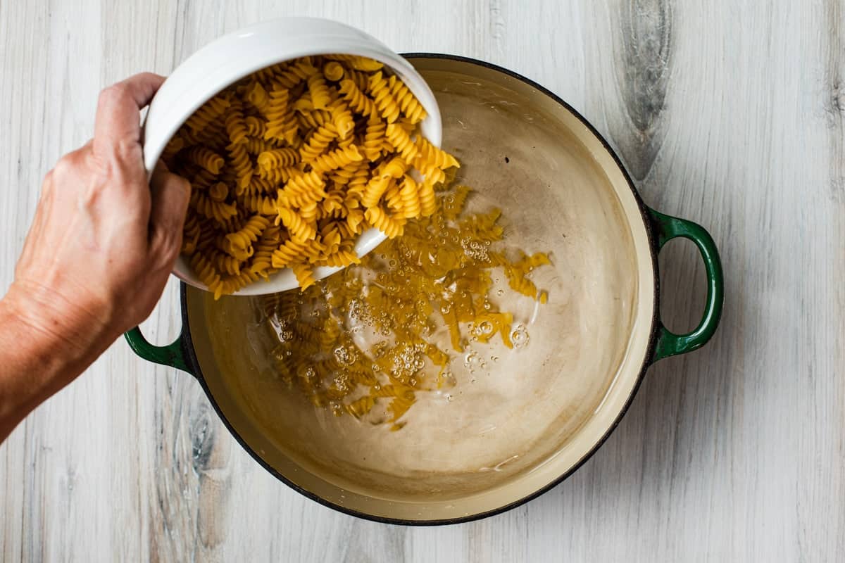 adding pasta to a pot of water