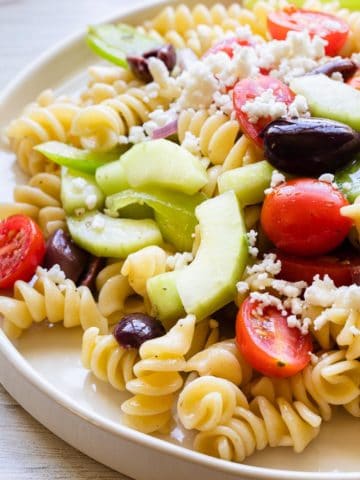 back lighting on a white plate of pasta salad