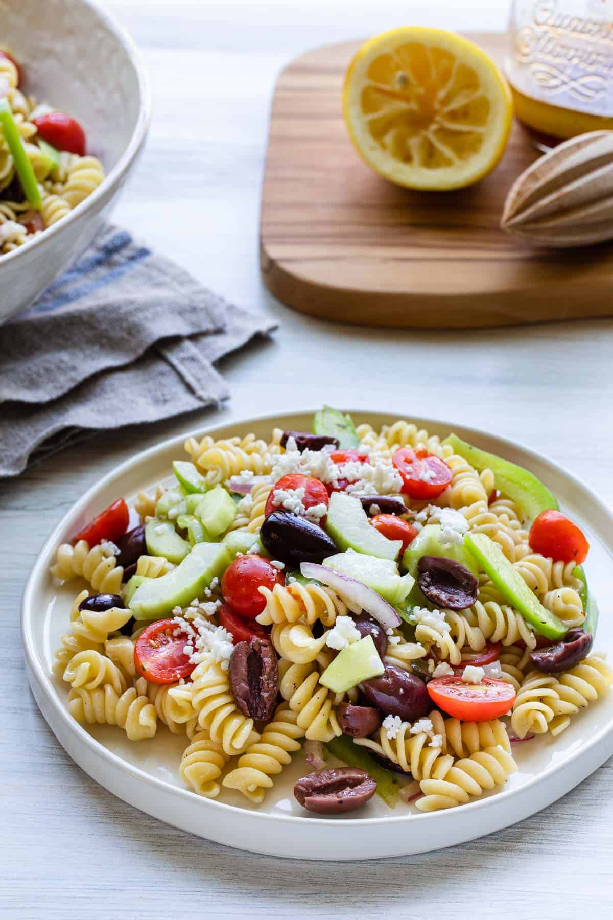 plate of rotini salad lemon on board in background