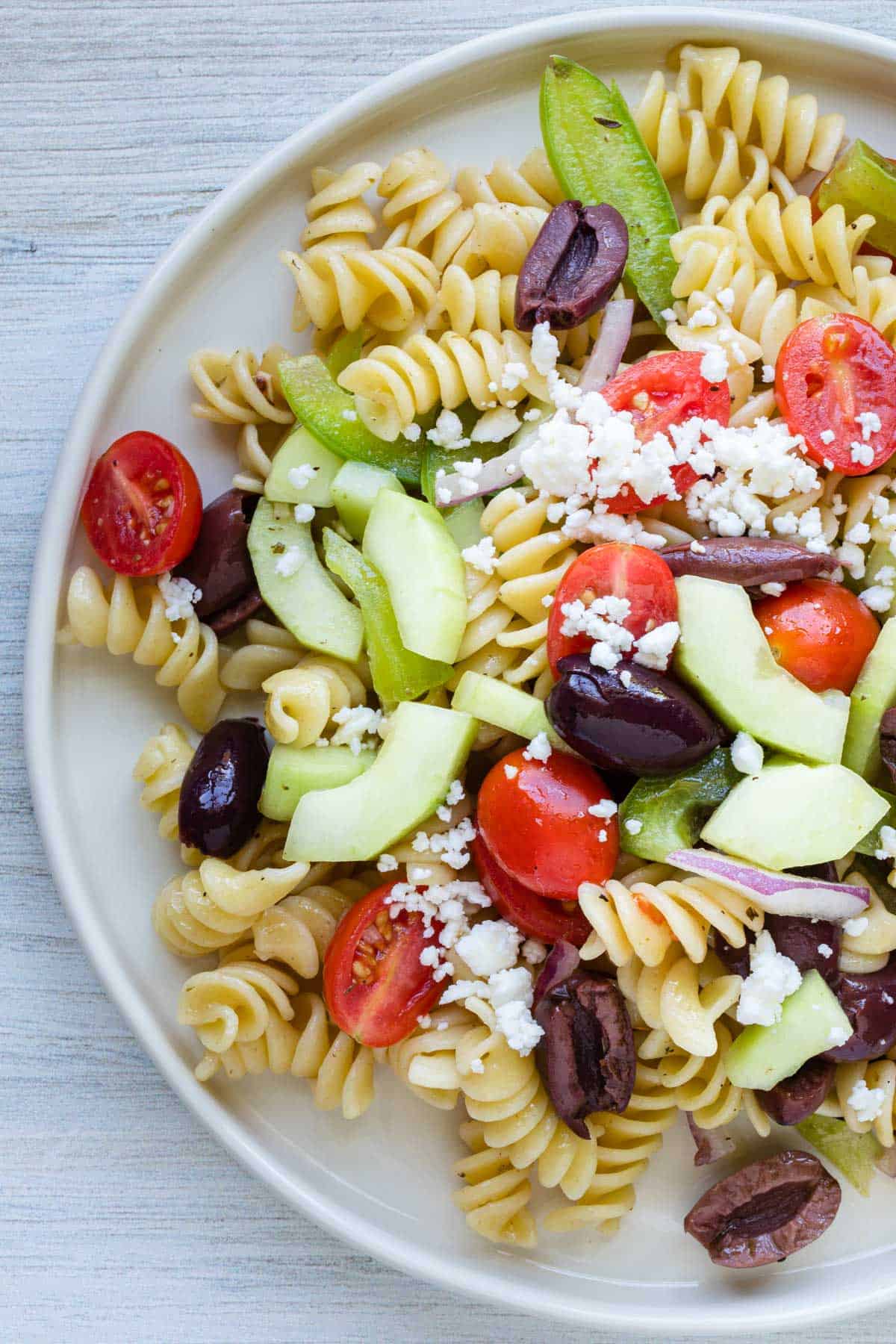 partial view of white plate with pasta salad