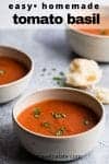 a bowl of soup with extra bowls and a hunk of bread in the background