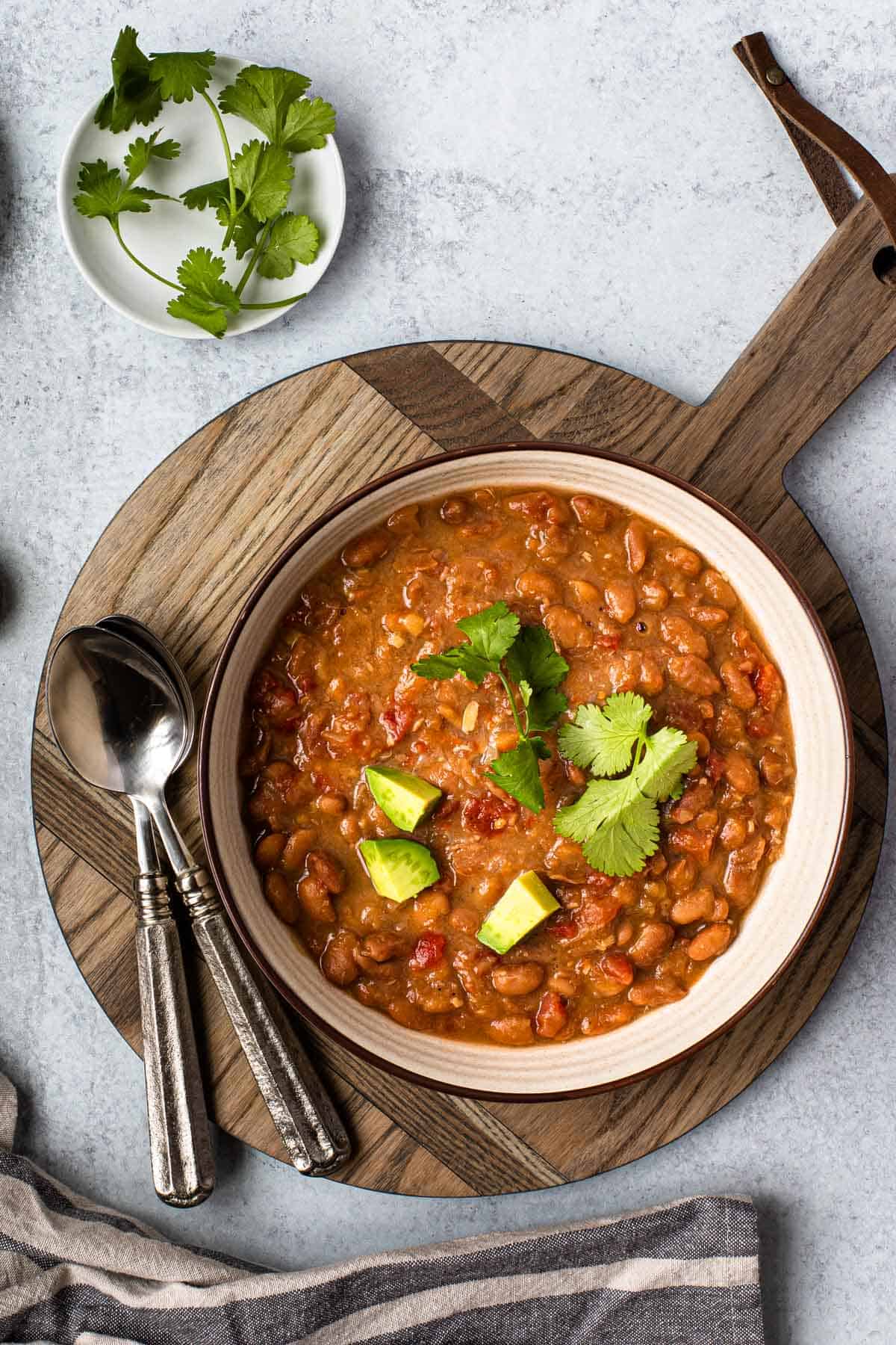 overhead shot of recipe in a bowl that's atop a wooden board with cilantro and spoons in background.