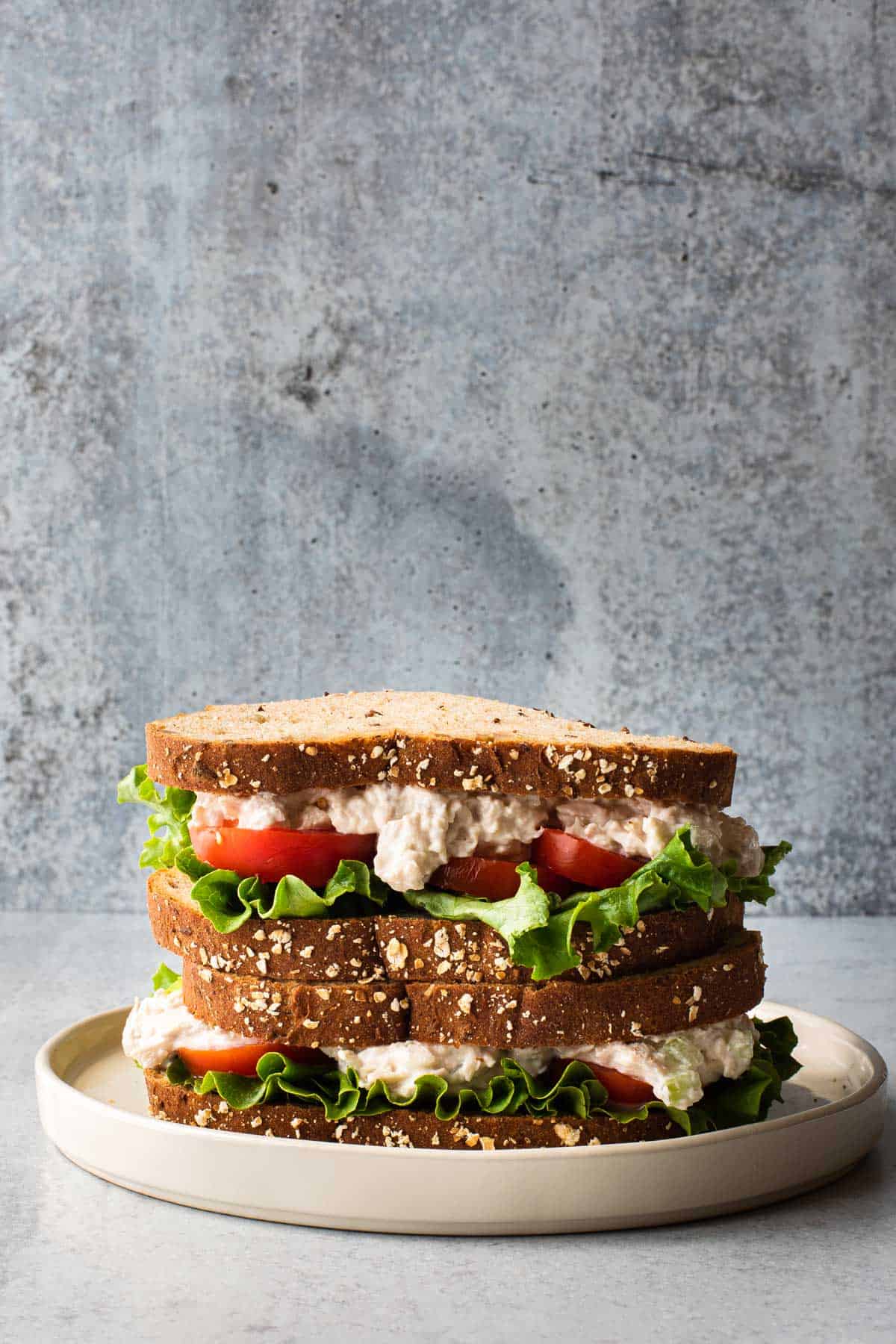 two sandwiches stacked on top of each other on a white plate with a gray background