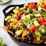 Nachos in a cast iron skillet loaded with garnishes.