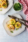 egg cups on two plates with green onions and a red and white stripped dishcloth