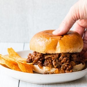 close up of easy sloppy joes with a hand picking up the sandwich