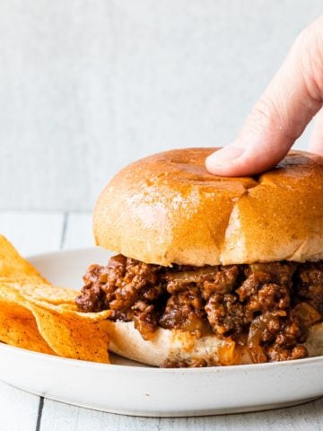 close up of easy sloppy joes with a hand picking up the sandwich