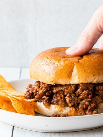 close up of easy sloppy joes with a hand picking up the sandwich