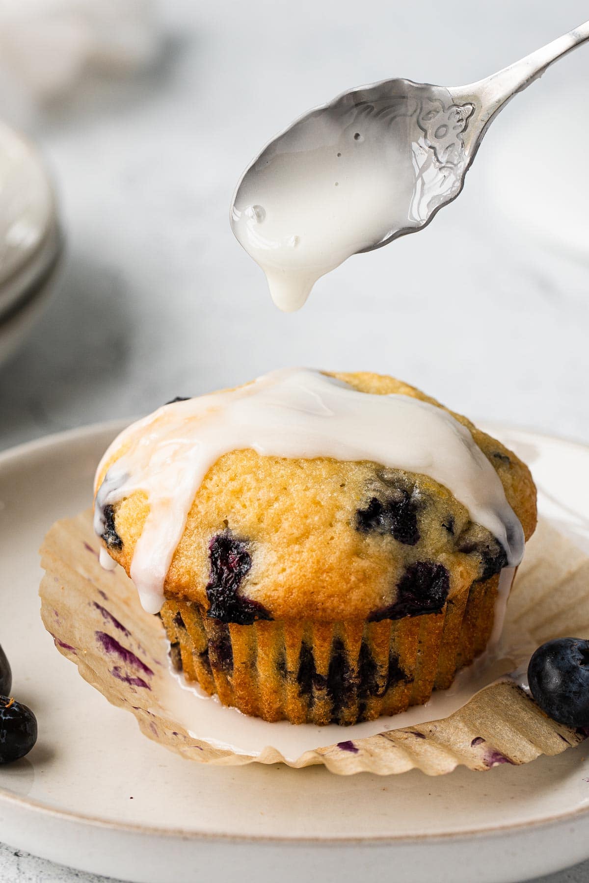 close up view of muffin getting drizzled with lemon glaze