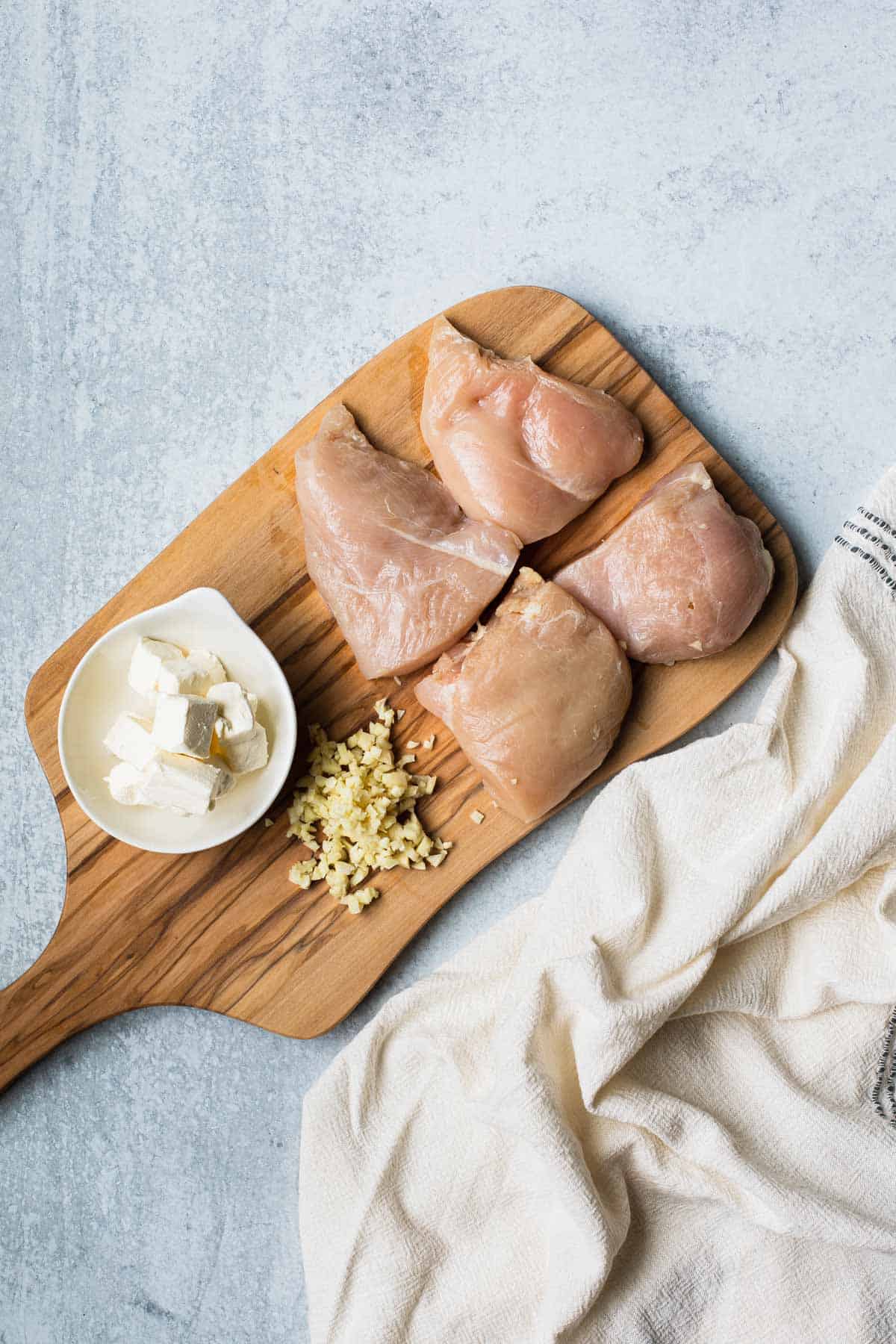 cut chicken, minced garlic, cubed cream cheese on a cutting board