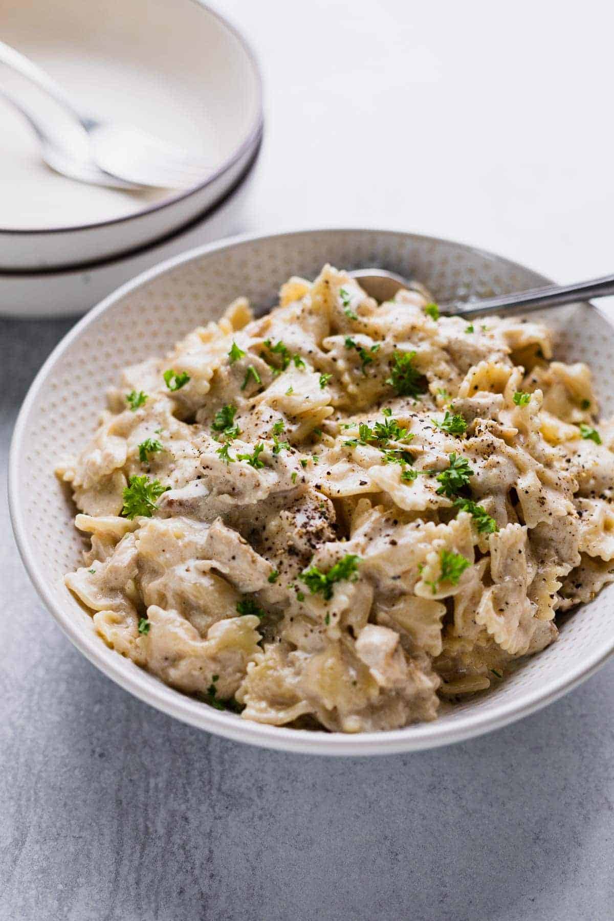 white bowl filled with pasta alfredo sprinked with parsley