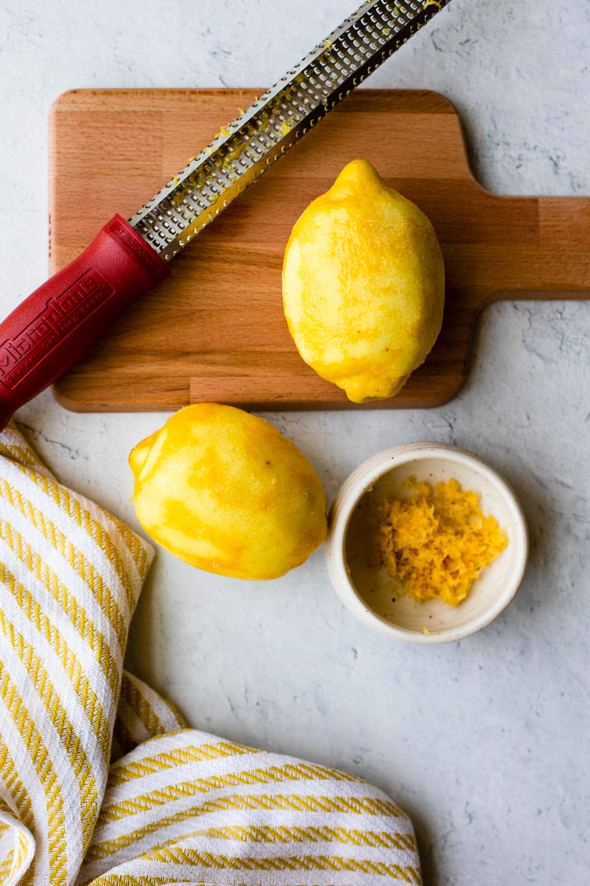 2 lemons with zest removed on a cutting board 