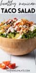 straight on view of salad in a wooden bowl with dressing drizzled over top