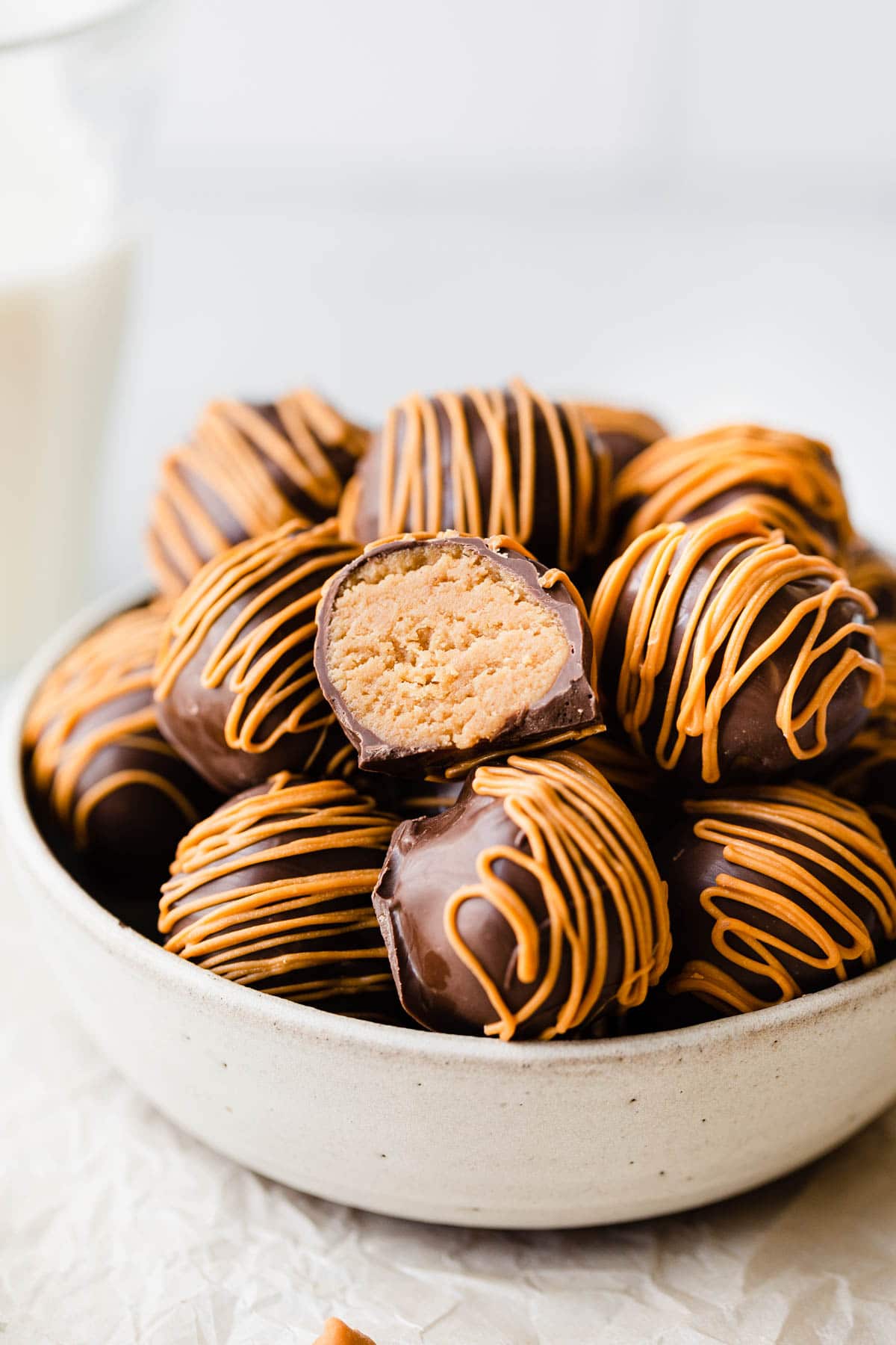 close up of peanut butter truffles in a bowl one truffle is cut open to show the filling