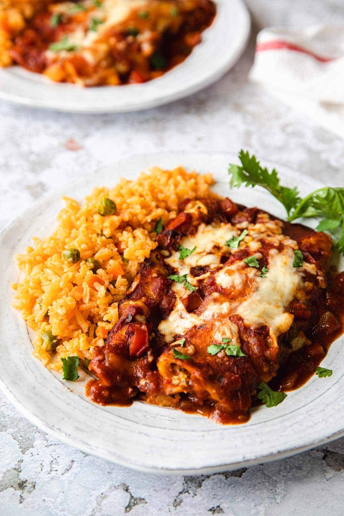 white plate with enchiladas and spanish rice on the side