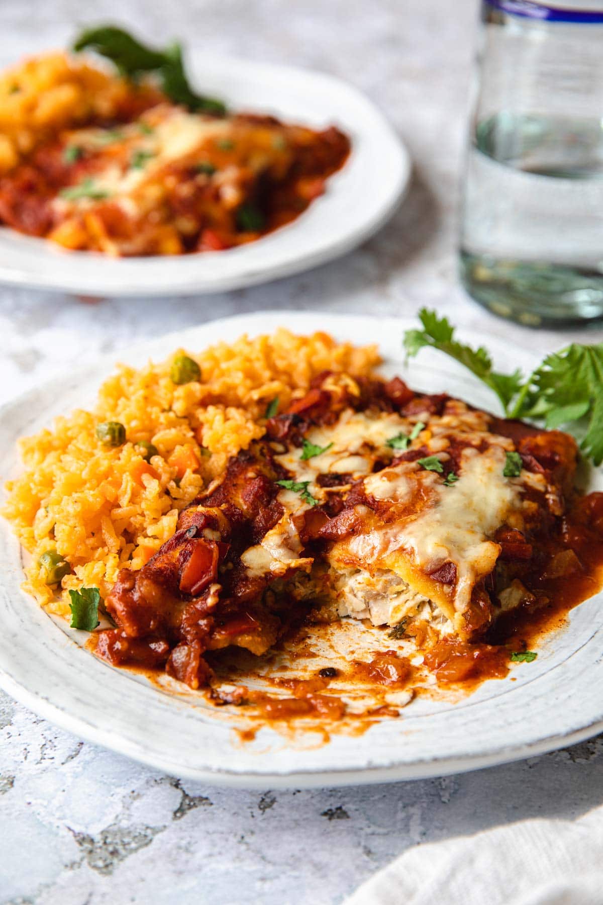 plate of enchiladas cut open to show chicken filling and a side of d spanish rice