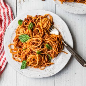 overhead view of a plate of spaghetti with basil leaves