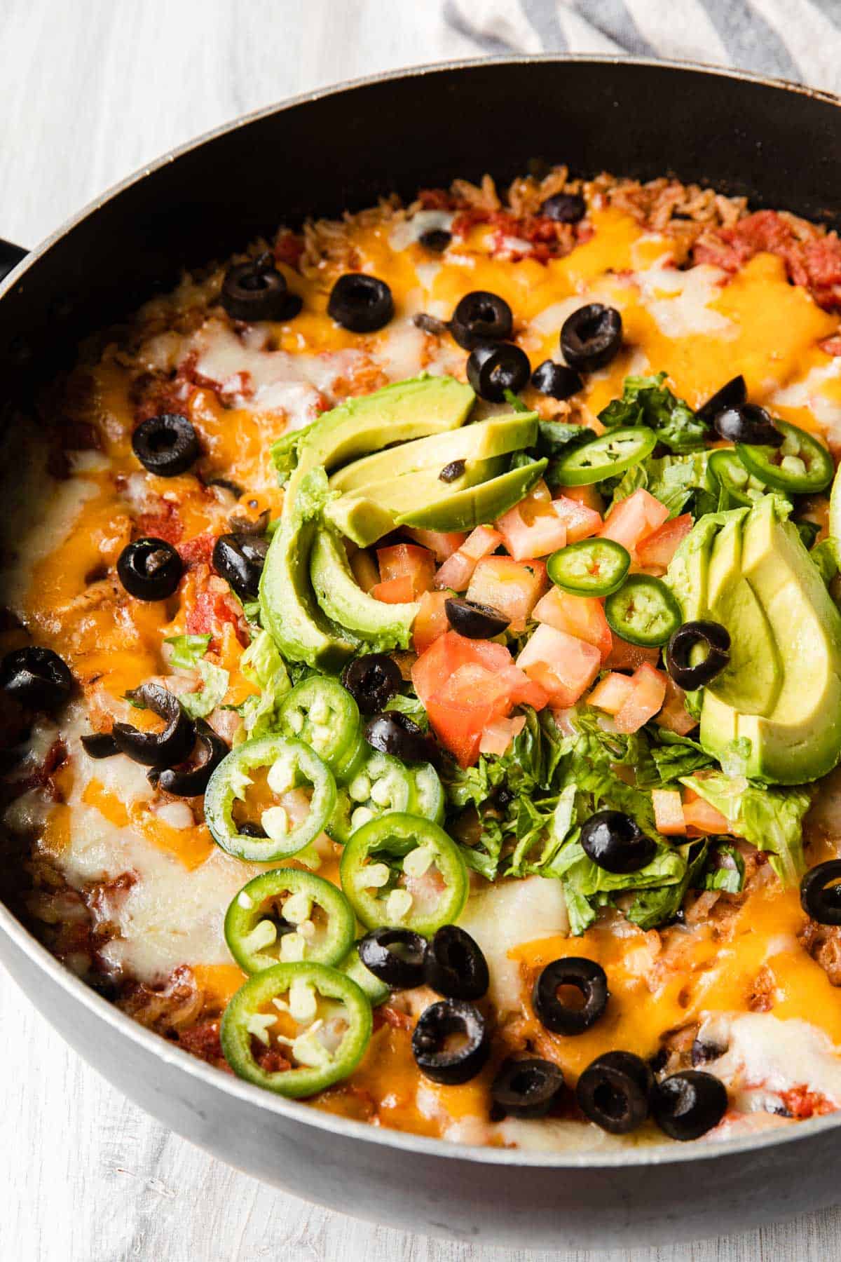 finished recipe in a large skillet topped with avocado and jalepenos