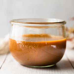 close up straight on view of caramel in a glass jar